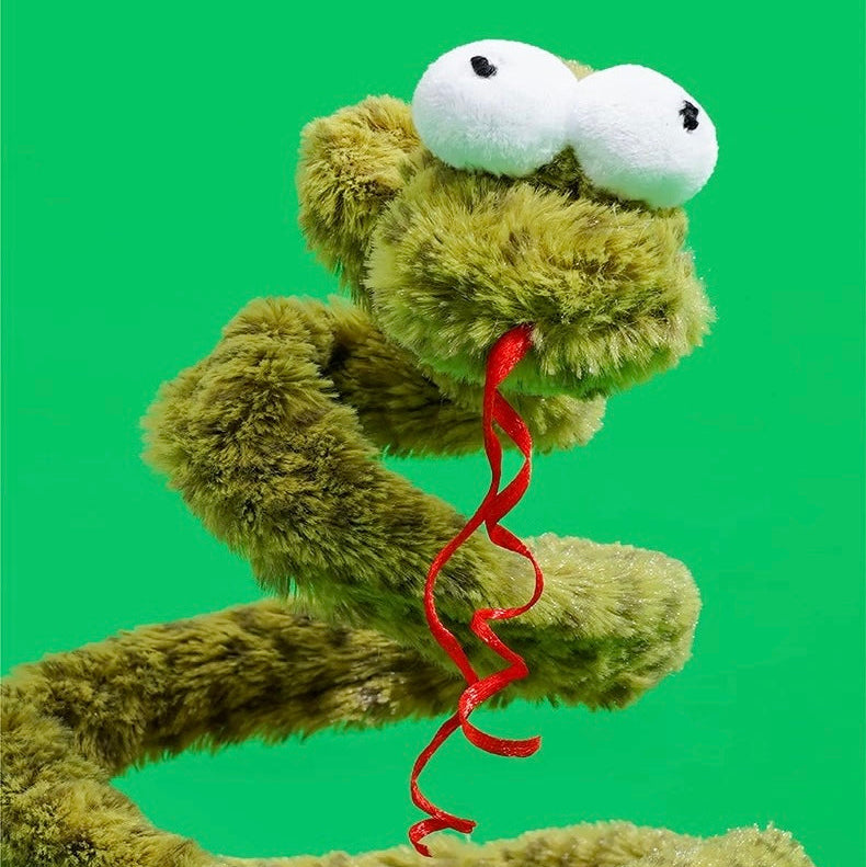 Green snake plush toy with red ribbon on a bright green background. Jouet intéractif.